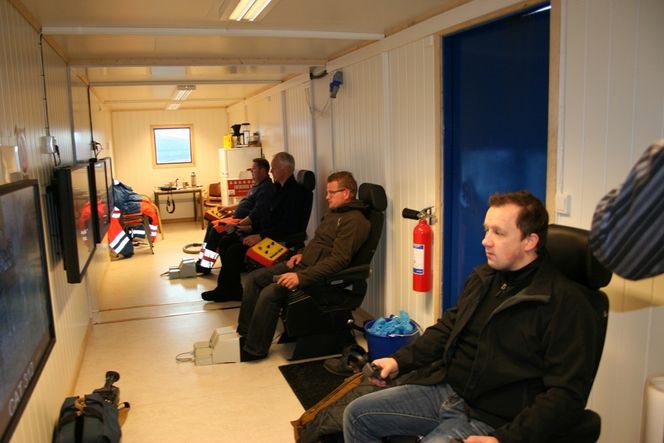 DATASPILL: Som en gjeng ivrige tenåringer med spillkonsoller sitter maskinførerne i en stålcontainer og følger med på skjermen mens de styrer maskinene. (FOTO: Sofus Gedde-Dahl)