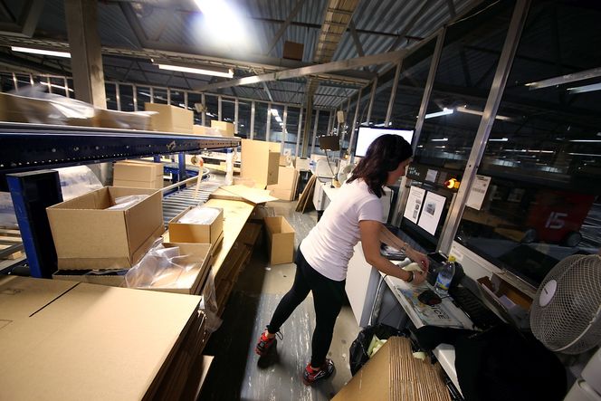 Hektisk: Når robotbilene har plukket varene sine, sendes de til en av totalt 27 plukkporter. Her tar Beata Starkner dem i mot, registrerer dem i systemet og plasserer dem i pakker med riktig adresseseddel.