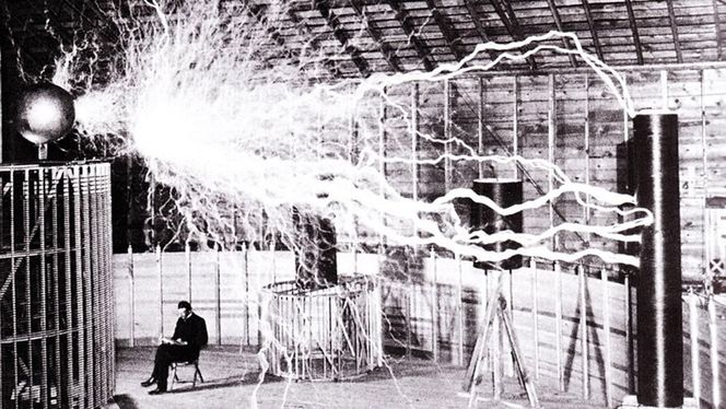 Nikola Tesla i laboratoriet i Colorado Springs, desember 1899. Bildet er dobbeleksponert - de elektriske strålene er tatt i et mørkt rom, mens Tesla og rommet er eksponert i etterkant.