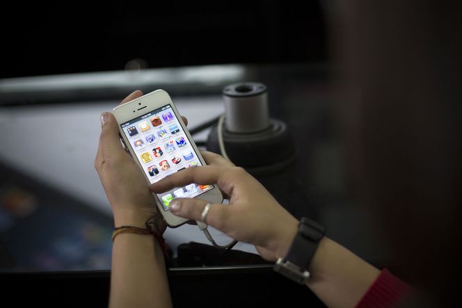 En indisk kvinne prøver iPhone 5 i Mumbai. Til høsten kan det komme en billigere utgave av iPhone, som vil kunne gjøre innhugg i viktige asiatiske markeder. Bilde: Brent Lewin/Bloomberg via Getty Images/All Over Press