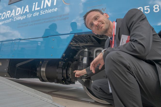 Konrad Steindorff er sjefingeniør med ansvar for fremdrift og brenselcellesystemet og peker på den elektriske asynkrone motoren som har erstattet dieselmotoren i det nye hydrogentoget. Foto: Odd Richard Valmot