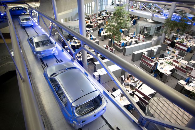 Biler i landskap: Mens de ansatte i administrasjonen i Leipzig jobber i åpent landskap, fraktes karosseriene fra en produksjonshall til en annen over hodene på dem. Arkitekt Zaha Hadid mente det ville minne dem på hva de faktisk jobbet med når de satt foran pc-skjermene. Foto: Mona Strande