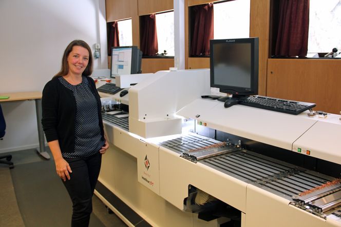 Digitalisering av historiske data sikrer kulturarven. Her står Anette Clausen, fagdirektør for tilgjengeliggjøring hos Arkivverket, foran en stor og rask skanner som brukes til digitaliseringen. Foto: Harald Brombach