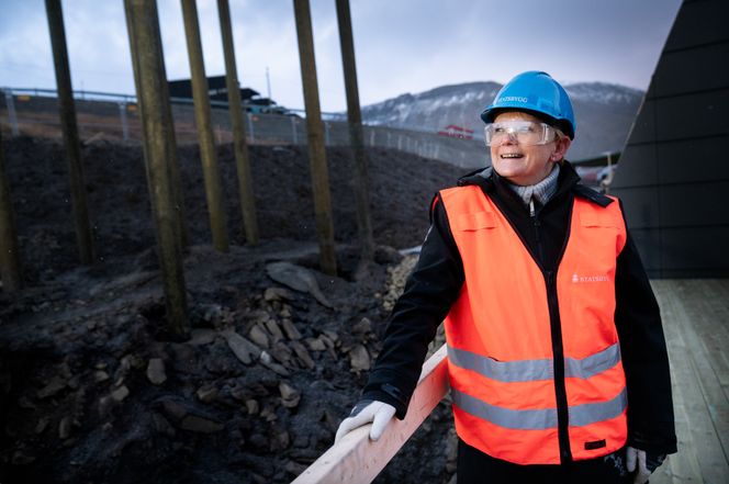 Inger-Johanne Tollaas forteller om et krevende prosjekt, men at det hittil har gått veldig bra. Bak skimtes fundamentet til lekeplassen. Foto:  Eirik Helland Urke