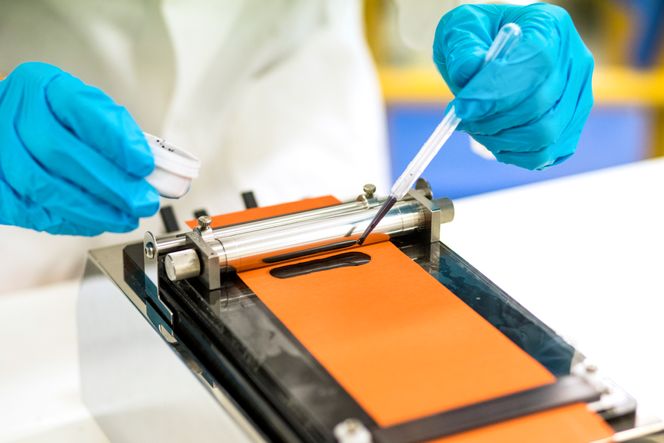 Kobber. Her legges en anodeslurry på kobberfoil. Anodeslurryen er en miks av fint grafittpulver, bindemiddel, eventuelt noe silisiumbasert materiale og andre tilsetnings-stoffer. Den presses til et jevnt lag, typisk med en tykkelse på 65 µm. Kobberfoilen fungerer som strømleder i battericellen for den negative elektroden/anoden. Foto:  Thomas Brun