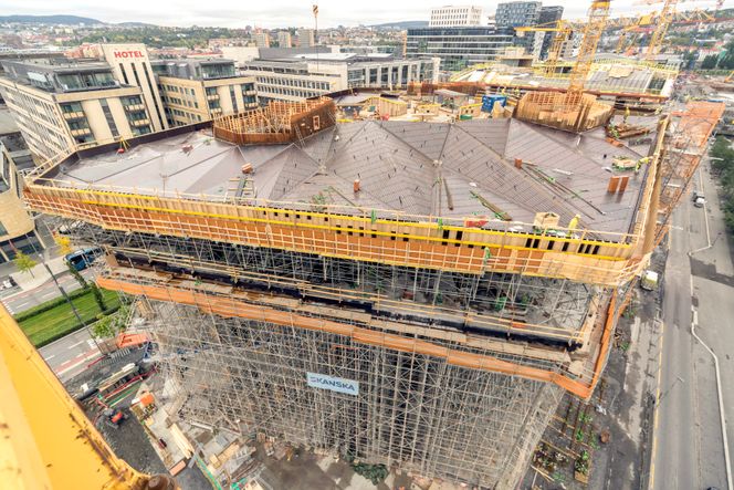 I byggeperioden måtte reisverket fra bakken tåle all vekt både fra utkragingen og foldetaket. Over betongtaket er det et regntett ståltak som følger foldetakets geometri, men med rom mellom som gir plass til inspeksjon, sprinkler og kabelføringer. Foto:  Doka Norge