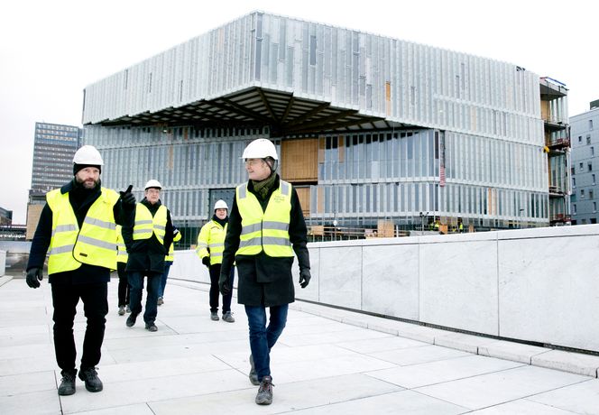 Den store utkrageren gir bygget mye ekstra areal uten å ødelegge siktlinjen til Operaen. Arkitektene Nils Ole Bea Brandtzæg (til venstre) og Einar Einar Hagem (til høyre) mener hensynet til arealutnyttelse også var årsaken til at de fikk ja til det uvanlige foldetaket. Bak dem går ingeniør Matthias Stracke og kommunikasjonssjef Kristine Hogseth Langfjord fra byggherre Kultur- og idrettsbygg Oslo KF. Foto:  Sverre Christian Jarild