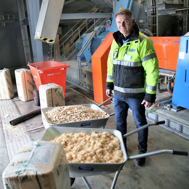 I den nærmeste trillebåra har Tom Wasenden finmalt flis, som brukes som blåseisolasjon. I den andre er det grovere flis, som brukes til isolasjonsplater. Foto: Knut Bjørheim