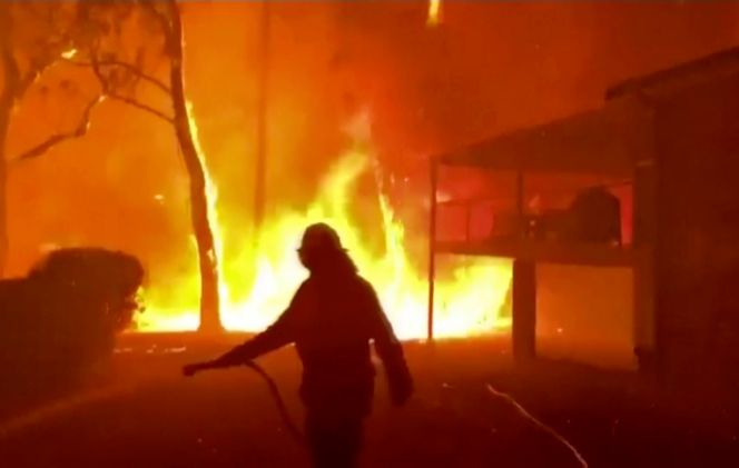 Bilde fra New South Wales Rural Fire Service, der en brannmann sprayer vann på en brann nært et hjem i Blackheath, New South Wales søndag. Foto: Twitter@NSWRFS via AP/NTB Scanpix