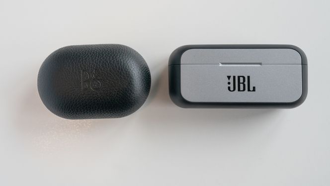 Dekselet på Beoplay E8 3rd gen er lite nok til å ha med i jakkelomma når man løper. Her ved siden av JBL Reflect Flow, som tar mer plass. Foto: Eirik Helland Urke