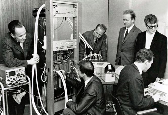 Norsk Datas første datamaskin, Nord-1. Fra venstre: Per Bjørge, Thor Monsen, Ove Raffelsen, Lars Monrad Krohn, Rolf Skår (ved tastaturet), Tom Weum. Foto: Fra boken «Norsk Data – hva gikk galt» av Tor Olav Steine