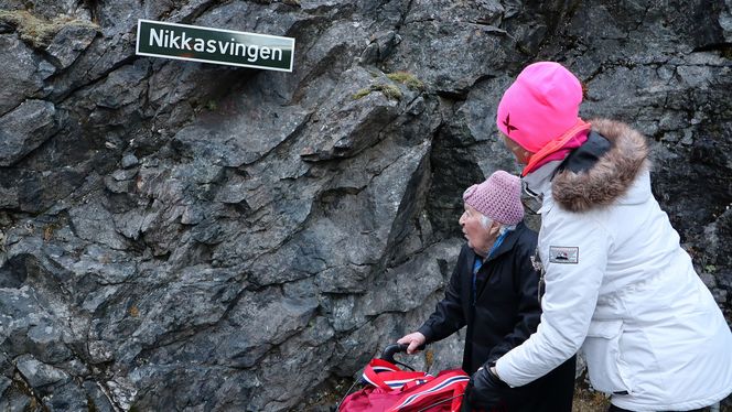 Nikoline Myren Grønning og fylkesordfører Tove-Lise Torve foran skiltet som viser at svingen ved Stigfossen for alltid skal hete Nikkasvingen, til ære for henne og de andre anleggskokkene som var med på å bygge Trollstigen. Foto: Foto:  Anne Marit Øksenvåg Johansen, Mære og Romsdal fylkeskommune