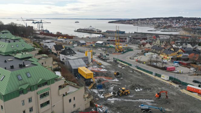 Rett nedenfor terasseleilighetene til venstre skal Bane Nor grave en opptil 35 meter dyp kulvert. Hele området fram til Bastøyferja i midten av bildet ligger i kvikkleiresonen som munner ut i fjorden. Foto: Bane Nor