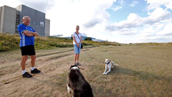 Utenfor Sizewell B og det nedlagte Sizewell A i Suffolk treffer vi flere turgåere langs strandpromenaden. Flere av dem ser positivt på at et nytt kjempeanlegg - Sizewell C - med hydrogenløsninger muligens skal bygges. Hundeeierne Lynne og Gary som bor i nærheten, sier man fort blir vant til nye anlegg når de først er bygget. Men de gruer seg litt til byggetiden på rundt ti år som vil føre med seg mye bråk og støy. Lokalbefolkningen forteller også at Sizewell B bevoktes av politistyrker dag og natt på grunn av terrorfare. Foto: Andreas Walstad