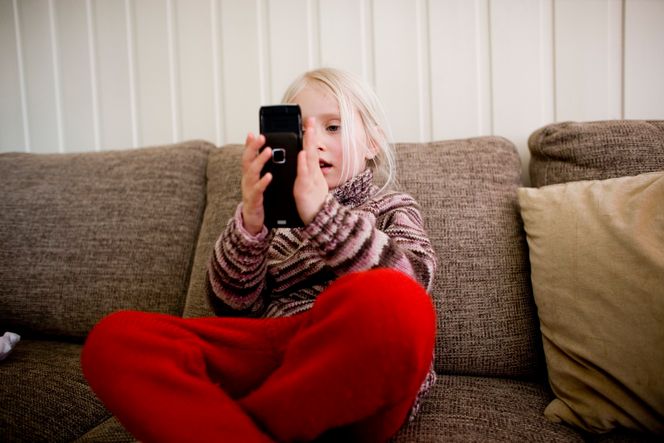 Inne på hytta kan det friste å være litt på mobilen. Foto: NTB