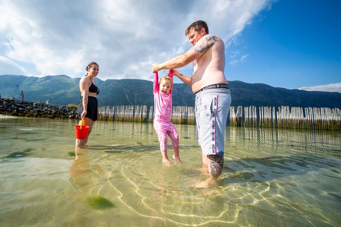 Kristine og Jon Eirik Fiplingdal og datteren Ellie fra Trofors nyter varmen og badeliv på bystranda i Mosjøen. Foto:  Heiko Junge / NTB