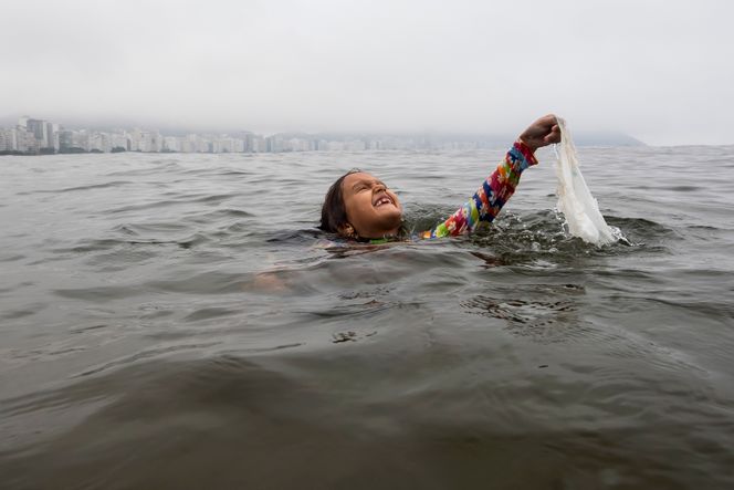 Nina Gomes henter en plastpose fra havet, nær Copacabana-stranden i Rio de Janeiro. Den åtte år gamle brasilianske miljøaktivisten har brukt årevis på å samle søppel i vannet på Copacabana-stranden og lære andre barn metoder for bevaring. Bildet er fra 2024. Foto: Bruna Prado/AP Photo/NTB