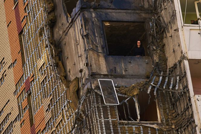 En kvinne titter ut av et vindu i en bygning i Kyiv truffet av en russisk drone Foto: Francisco Seco / AP / NTB