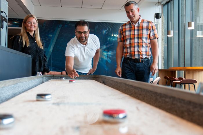 Maren-Elise, Sukhmeet og Hans-Petter tar seg et lite avbrekk med shuffleboard. <i>Foto:  TUM Studio</i>