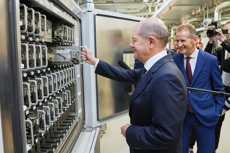 Tysklands forbundskansler Olaf Scholz setter en testcelle i testkammeret. VW-sjef Herbert Diess i bakgrunnen. <i>Foto:  Volkswagen AG</i>