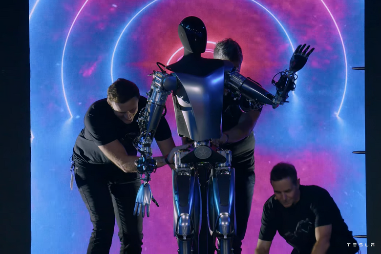 Tre menn måtte til for å trille roboten som er "svært nær det som skal komme i produksjon" ut på scenen. <i>Skjermbilde:  Tesla</i>
