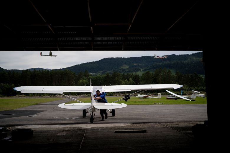 Pilot og fotograf Garrett Fisher dytter flyet sitt inn i en hangar på Voss. <i>Foto:  Bram Janssen</i>