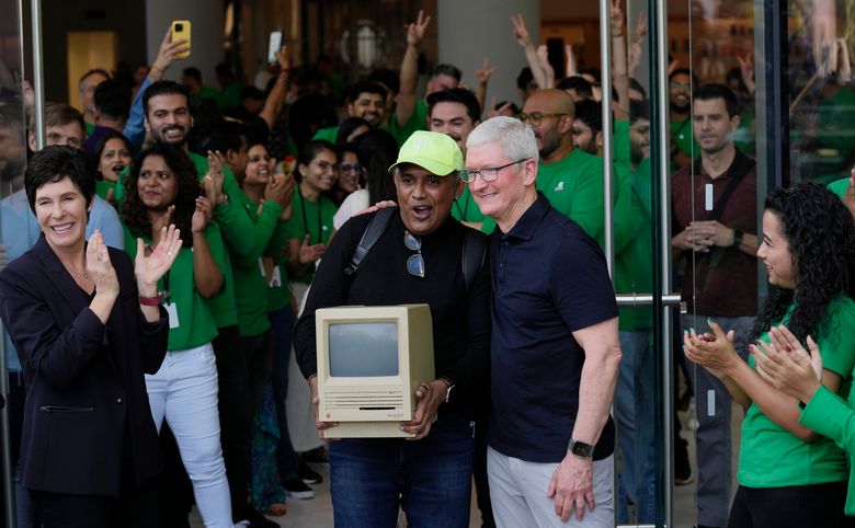 Apple-sjef Tim Cook (t.h.) sammen med en person som holder en gammel Macintosh-maskin. <i>Foto:  Rafiq Maqbool/AP/NTB</i>
