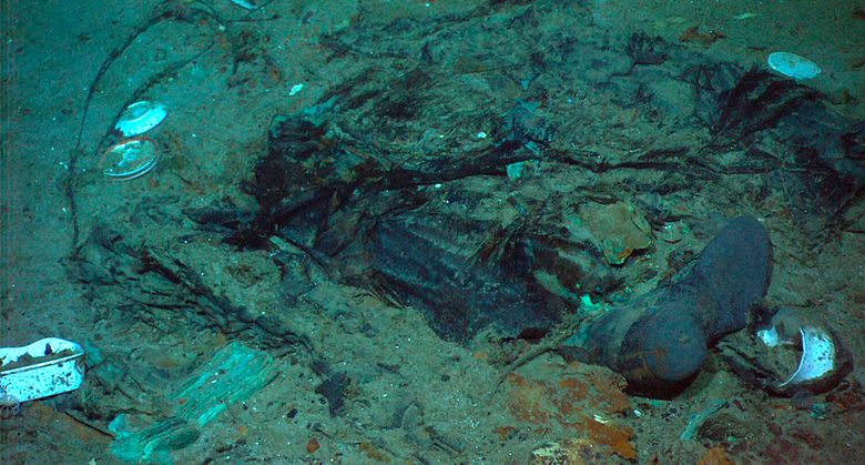 Rester av en frakk og støvler på havbunnen i nærheten av Titanic-vraket. Letingen etter ubåten Titan, som var på vei ned til vraket, er særdeles vanskelig, forteller eksperter. <i>Foto:  AP / NTB</i>