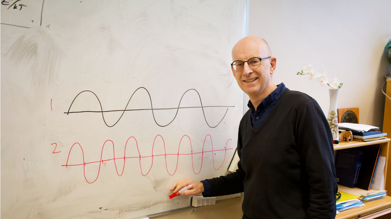 Professor Sverre Holm har tegnet om sinuskurven til en tone hvor den nederste er én oktav høyere, altså at den har dobbelt så høy frekvens. <i>Foto:  Elina Melteig/UiO</i>