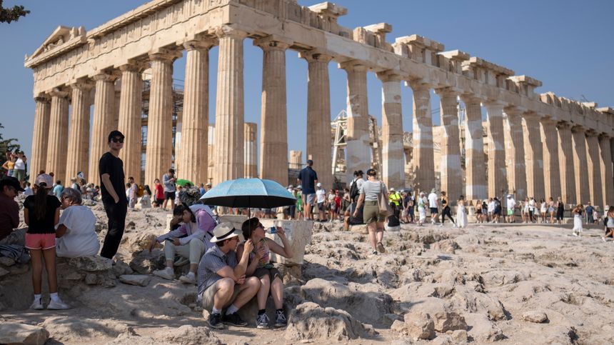 Turister kjøler seg ned i skyggen ved Parthenon-tempelet på Akropolis før helgen. Foto:  Petros Giannakouris