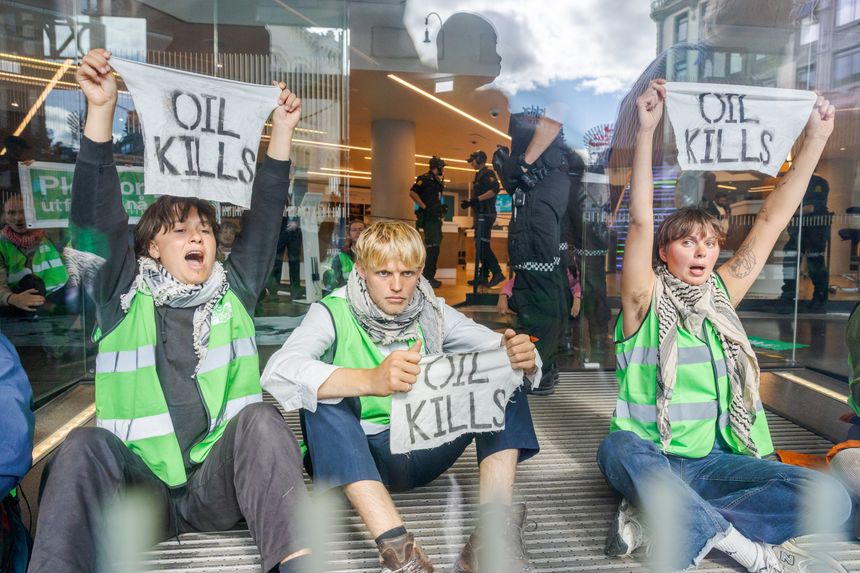 Aktivister fra Extinction Rebellion hever sine bannere under en aksjon ved DNBs lokaler i Karl Johans gate i sentrum. Foto:  Arash A. Nejad