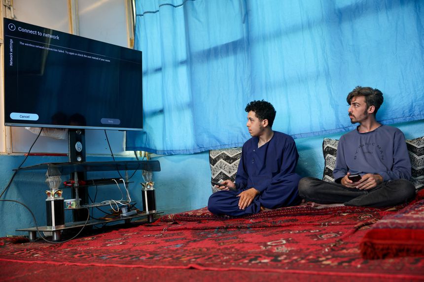 Afghanere forsøker forgjeves å koble til TV-en sin til internett. Bildet er tatt i Kabul, 30. september. Foto:  Sayed Hassib/Reuters/NTB