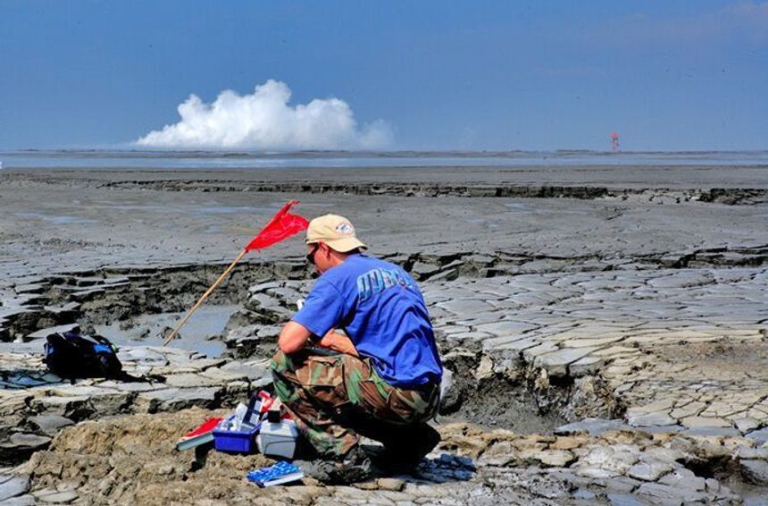 Adriano Mazzini tek prøver av væske ved Lusi-mudderutbrotet, Indonesia. Ein geysirfase ved krateret kan sjåast i bakgrunnen. Foto: Privat