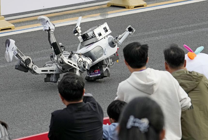 Det er ikke bare-bare å stokke beina riktig. En annen robot måtte bæres bort på båre. Foto:  Iori Sagisawa/Kyodo News/AP/NTB