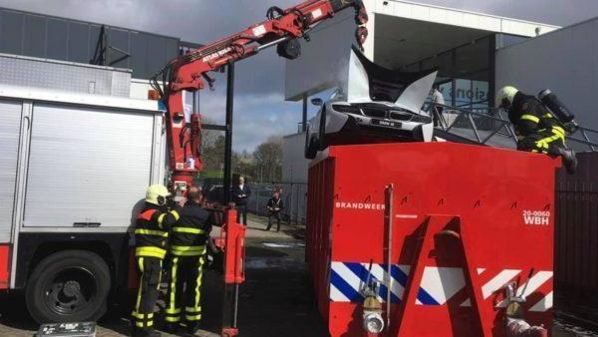 Brannfolk senker en BMW i8 plug-in hybrid ned i en container med vann for å kjøle ned en brann i bilens lithium-ion batteri.