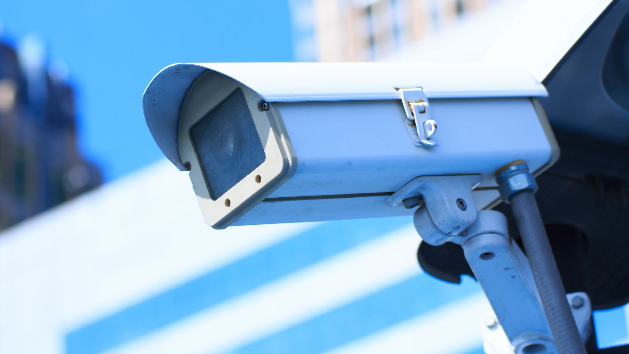 Camera system guarding blue skyscraper office building with sky above