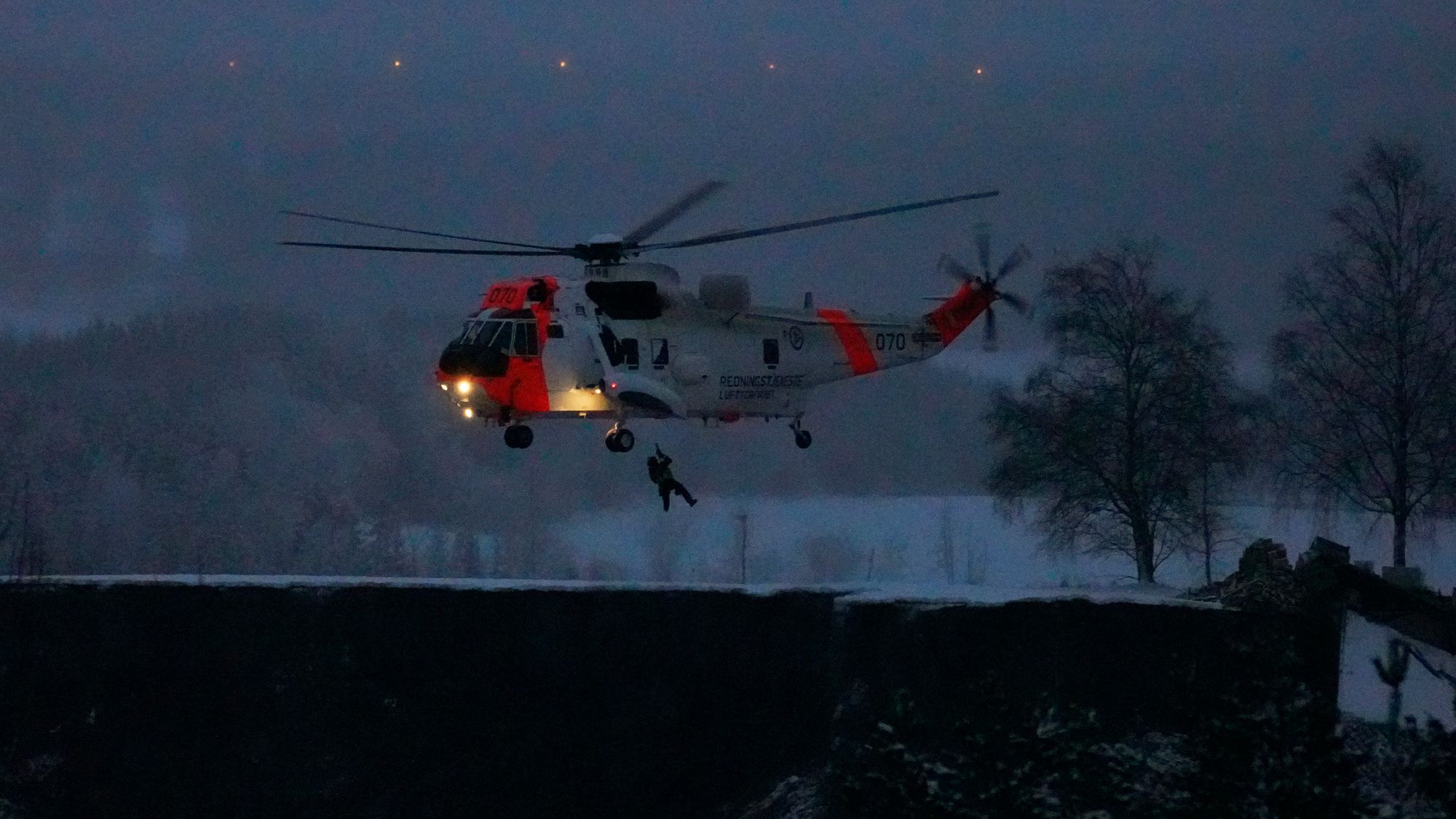 Et politihelikopter over rasstedet nyttårsaften idet mørket senker seg over rasstedet.