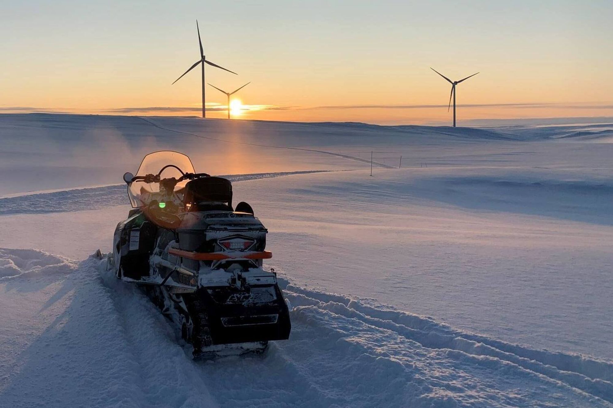 Snøscooter i solnedgang i Hamnefjellet vindkraftverk i Båtsfjord.