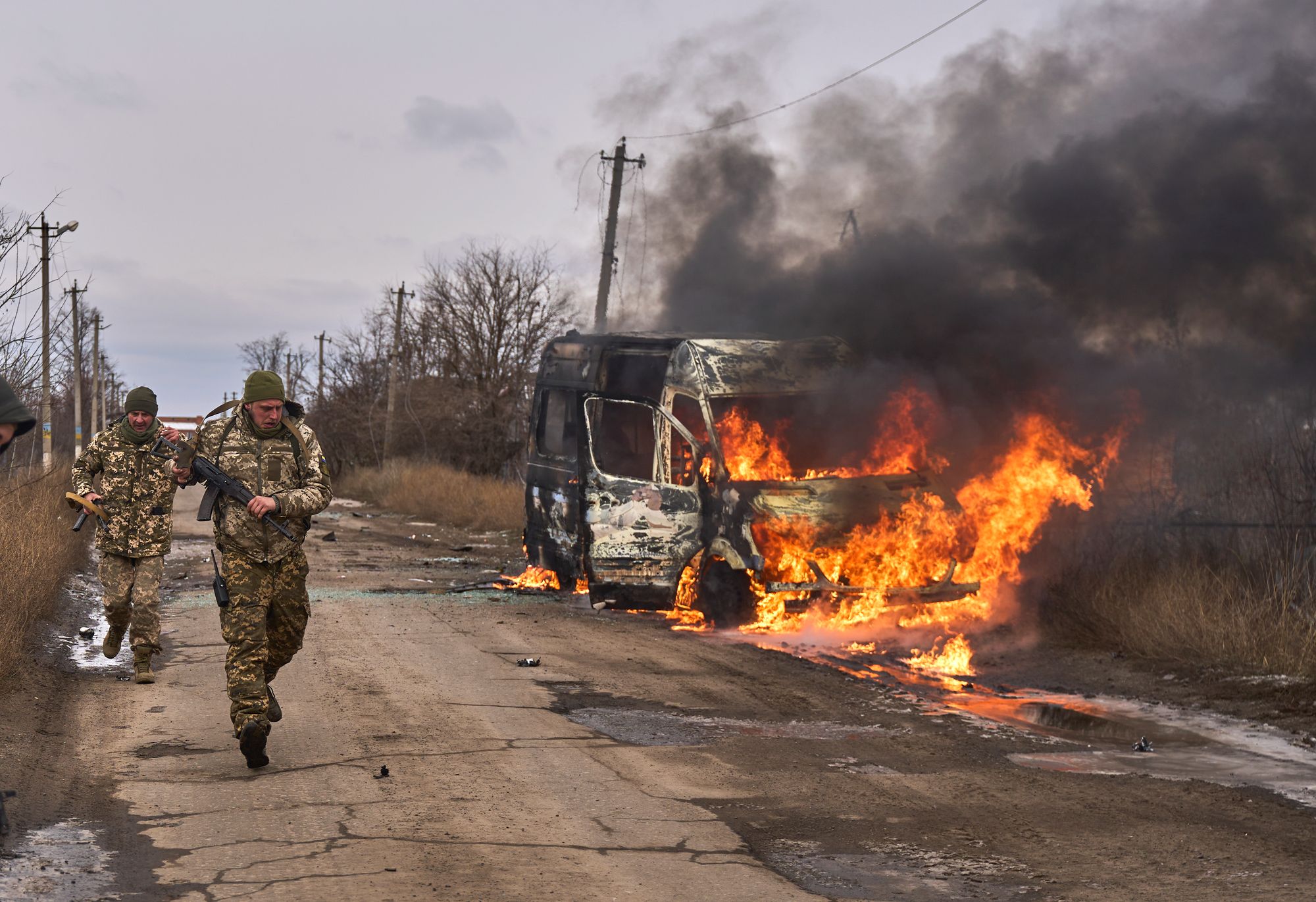 Ukrainske soldater passerer en brennende buss som har blitt truffet av en russisk drone nær Bakhmut i Dontesk-regionen i 2023.