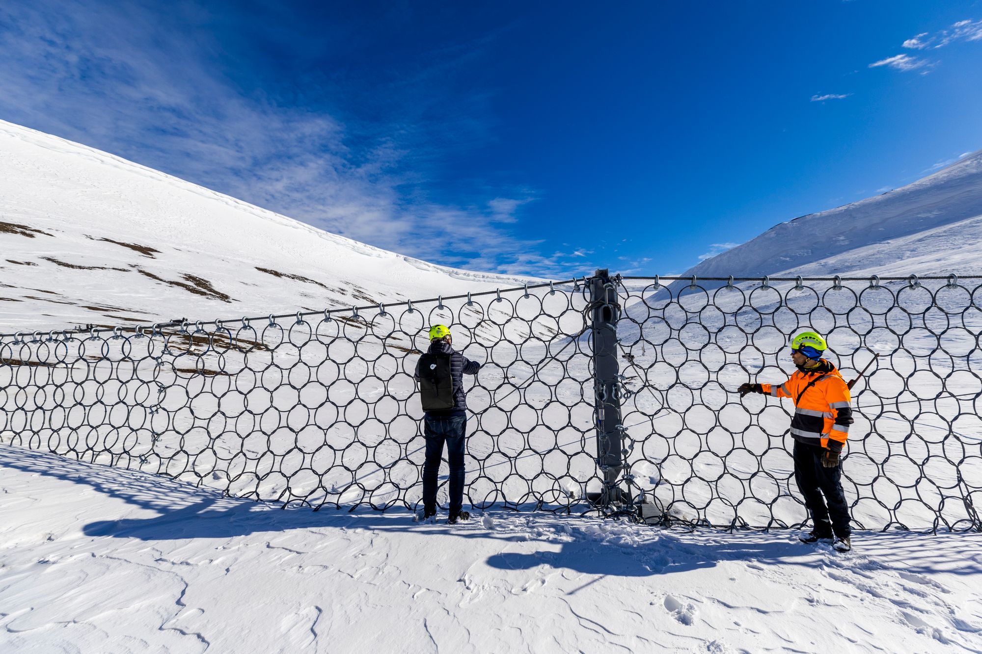 LONGYEARBYEN, SVALBARD 20240527
Skredsikring i Vannledningsdalen i Longyearbyen på Svalbard. Alt fraktes opp med helikopter, men håndteres av installøtørter fra østerikere med muskelkraft for å komme på plass på fjellsiden.
Sverre Mejlænder-Larsen, prosjektleder for totalentreprenør LNS Spitsbergen. Mannen med gevær.
Han hadde med seg gevær i tilfelle møte med isbjørn.
Nettet på toppen av vannledningsdalen er på to meter nå, men skalbli seks meter når den står ferdig.
Foto: Arash A. Nejad