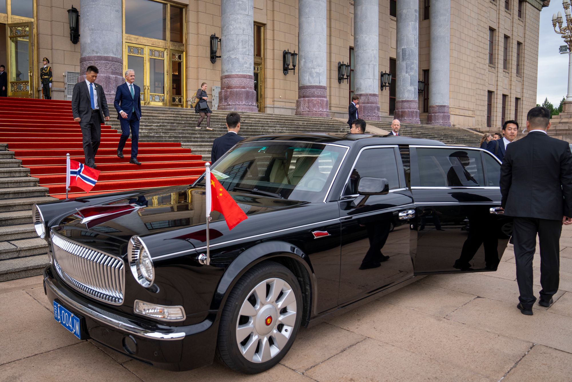 Statsminister Jonas Gahr Støre (Ap) forlater Folkets store sal i Beijing etter et møte med Kinas statsminister Li Qiang tirsdag. Nedenfor trappen står den karakteristiske retrobilen og venter på ham. 