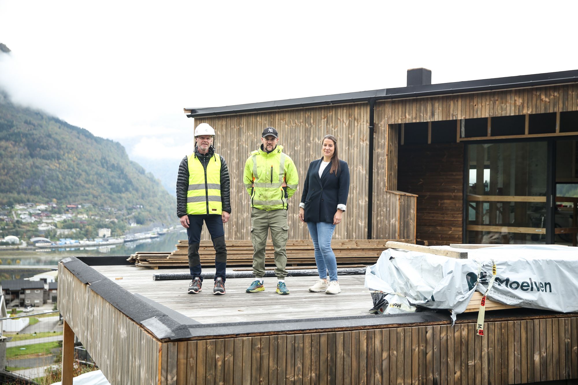 Miljørådgiver Ola Rise (t.v.) i Stiftelsen Miljømerking Norge, prosjektleder Håvard Maurset i Nordfjord Hus og daglig leder Therese Lunde Solberg i Nordfjord Hus på en av terrassene i det nye svanemerkede huset på Hol i Stryn.