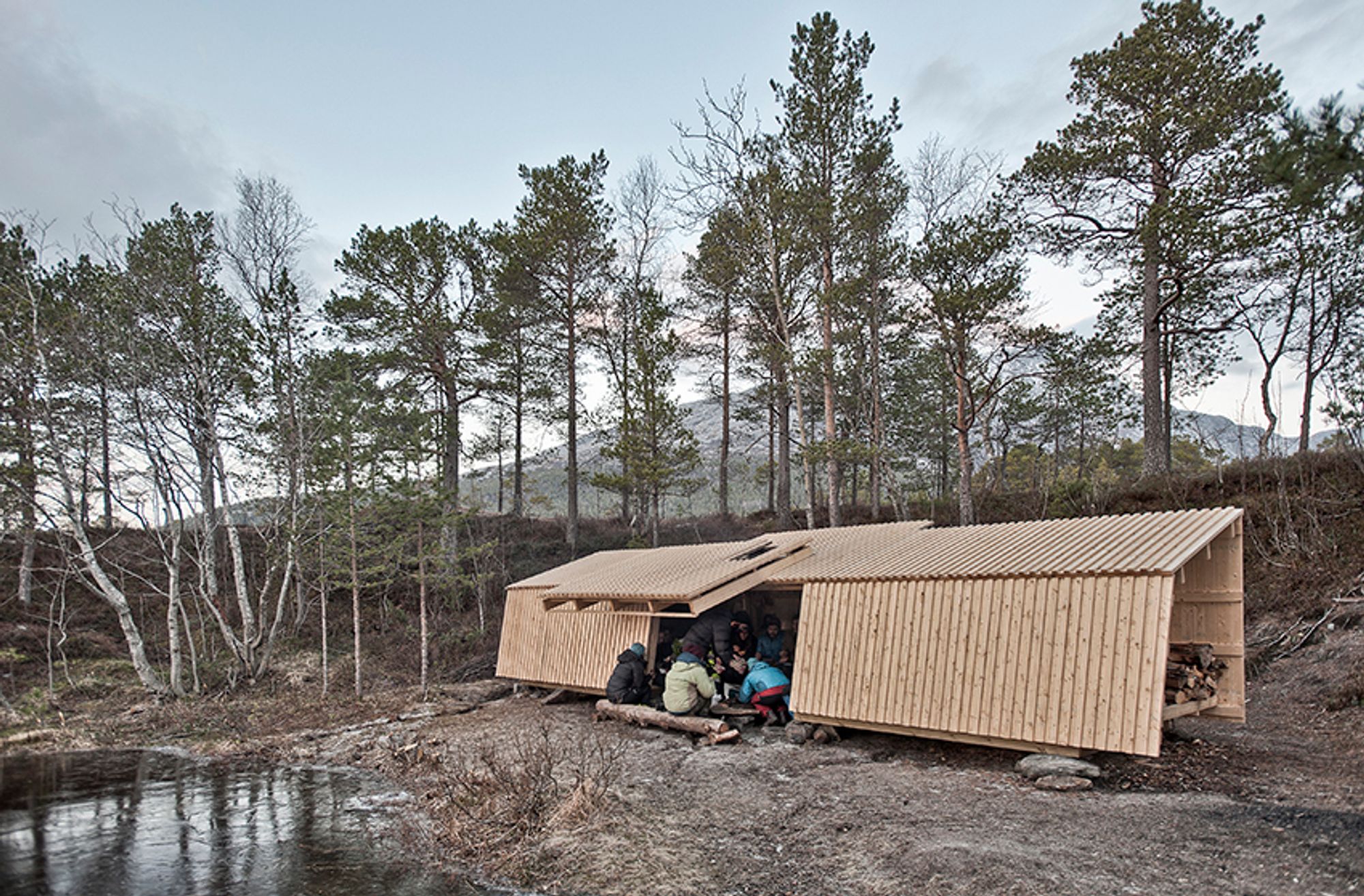 Dette er Heggmoen Campsite. Oppgaven fra Bodø friluftsavdeling var å lage et bygg som ga beskyttelse mot vær og vind og samtidig ga utsikt til naturen omkring og slapp inn dagslys i «tilfluktsrommet». Heggmoen er et badested med sandstrender, der det grunne elvevannet blir ganske varmt om sommeren. Men resten av året er klimaet arktisk og røft.