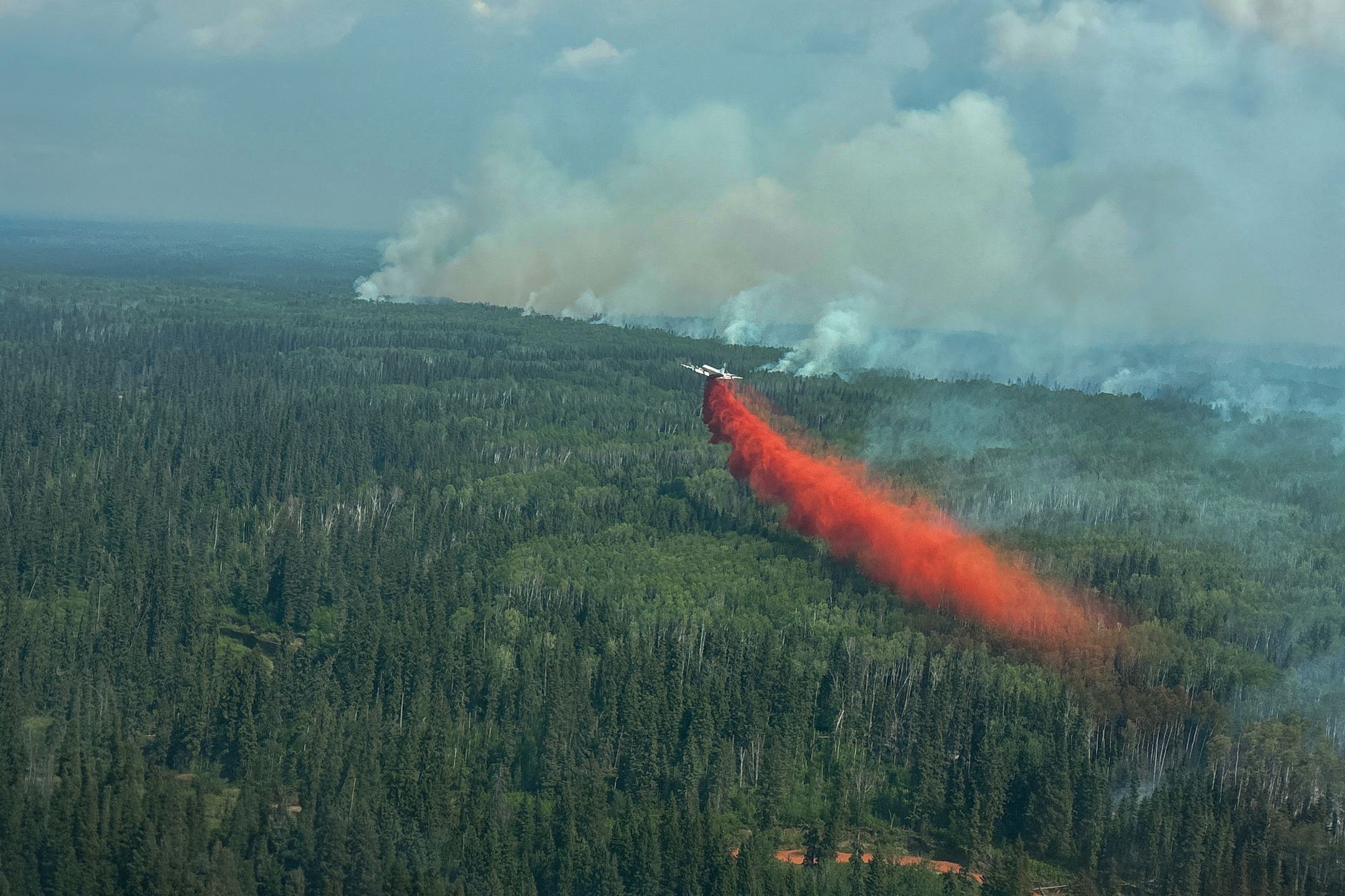 Vårens skogbranner i Canada er voldsommere enn vanlig, og noe av røyken når helt til Europa.På bildet slippes brannhemmende væske ut over brannen ved Sousa Creek i Alberta.