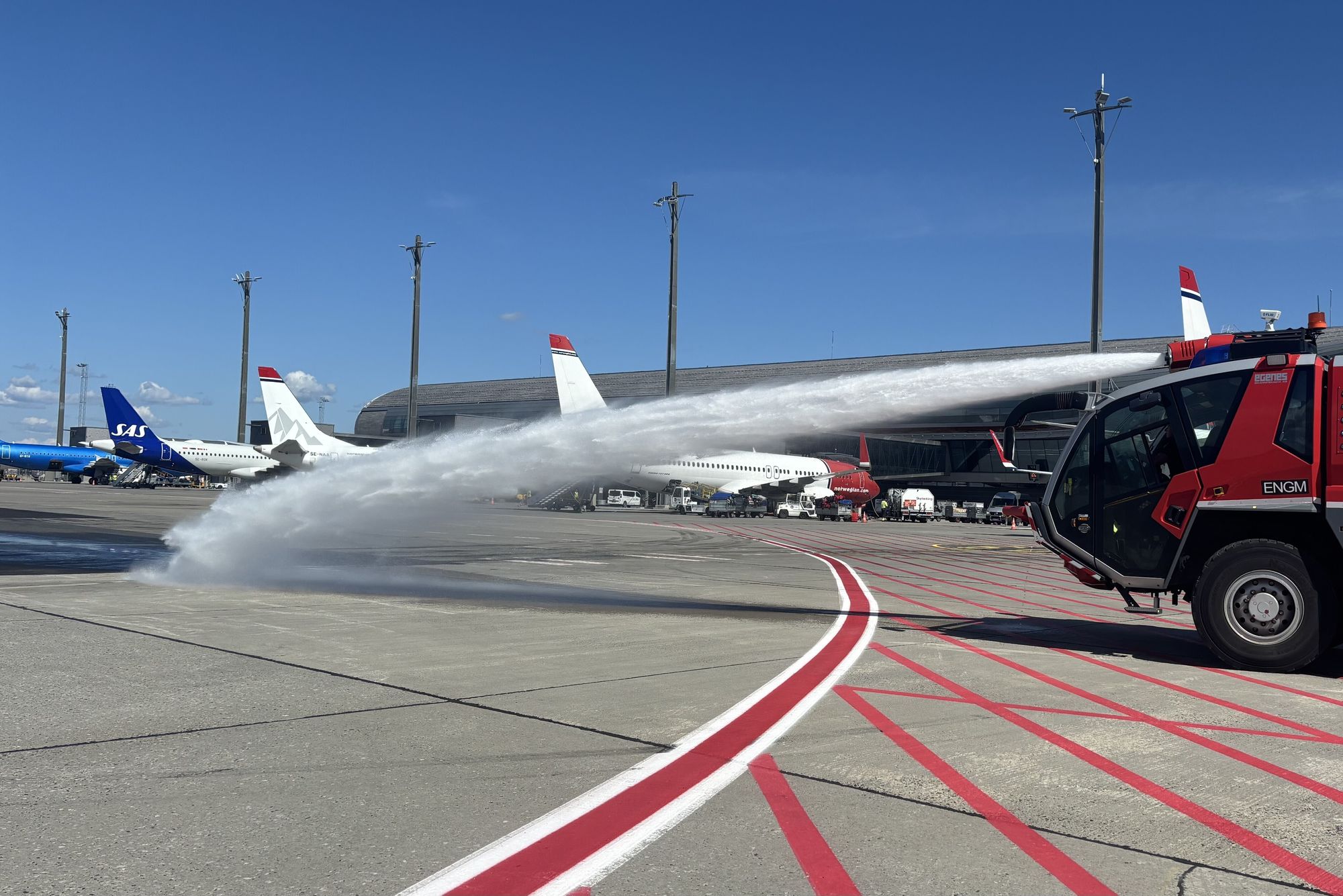 Brannbilene må ut og redde asfalten på Gardermoen i solsteken. Belastningen er spesielt stor der flyene dyttes ut fra gate og må dreie nesehjulet rundt på stedet hvil. Etter en kjapp avklaring med flygelederne i tårnet får brannbilen tillatelse til å kjøre ut på området.