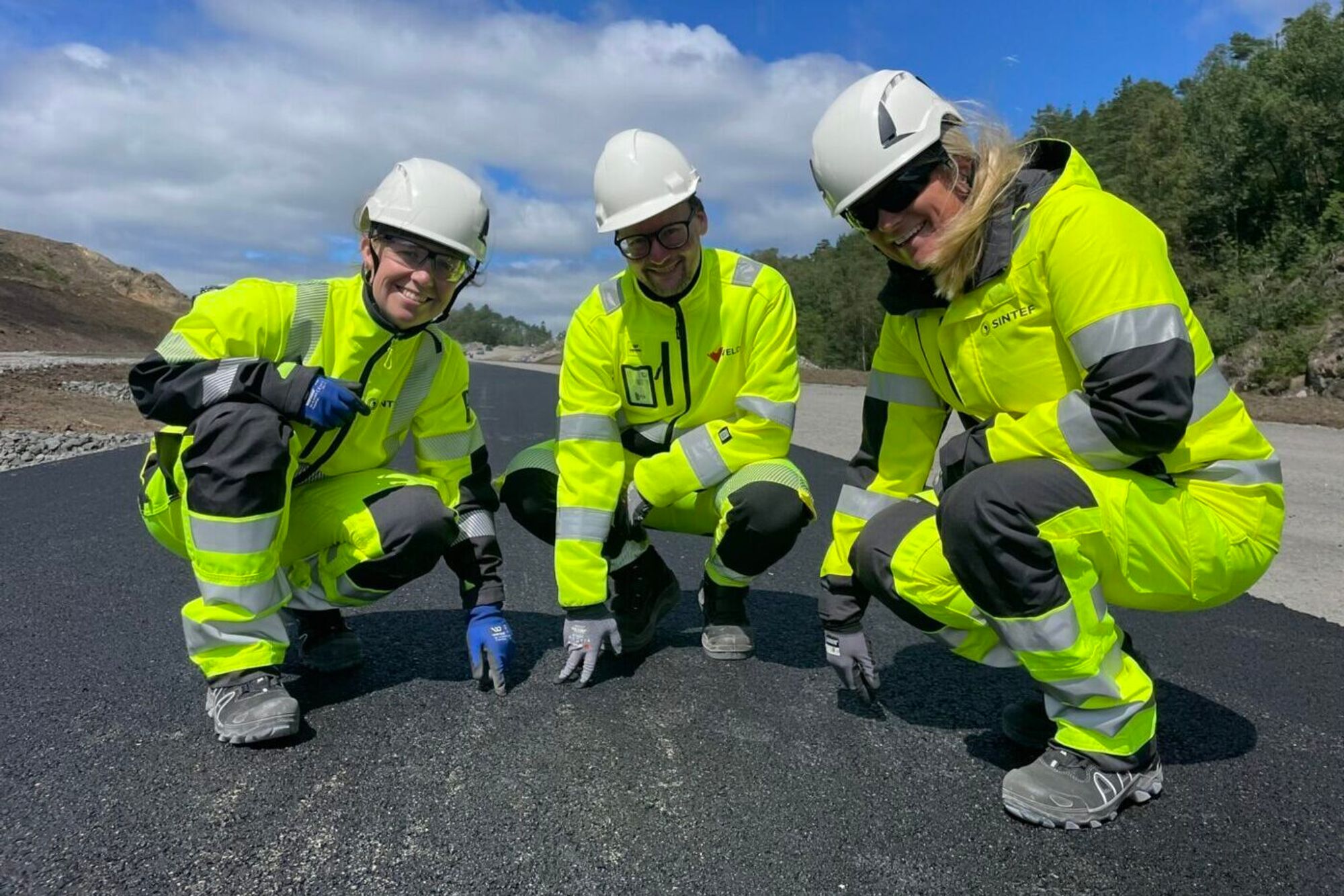 Du merker ikke forskjellen når du kjører her – men Marit Fladvad (t.v.) i Sintef), Petter Fossheim hos Velde Asfalt og Sintefs Lillian Uthus Mathisen viser hvordan det ser ut når E39 får sirkulær asfalt.