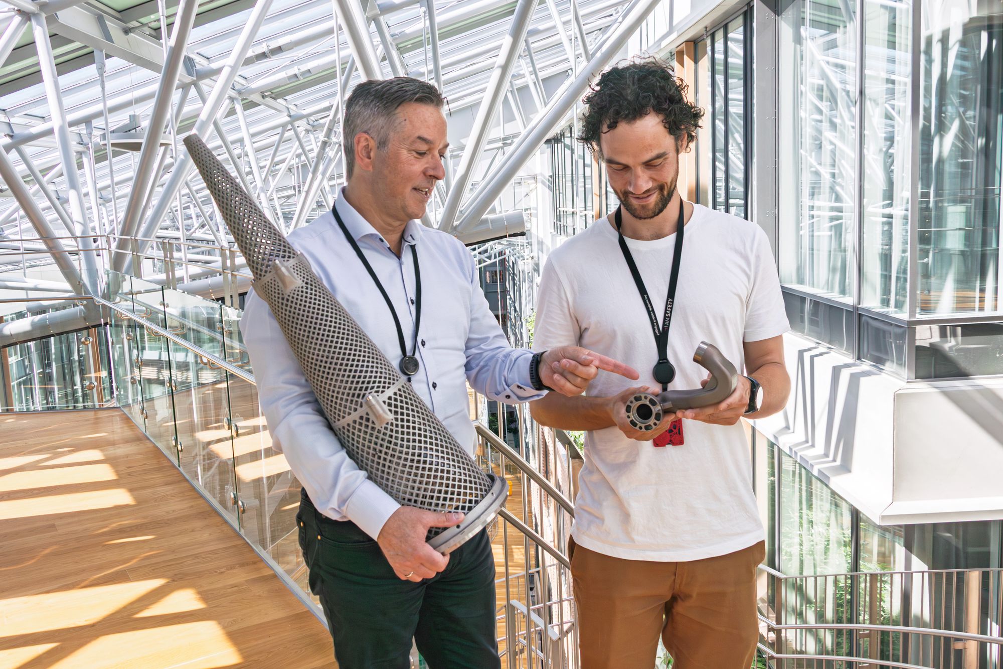 Brede Lærum (t.v.), som er sjef for 3D-print i Equinor, og 3D–print-ekspert Kristoffer Haugland viser frem to deler Equinor har fått 3D-printet. Det sparte dem for både tid og penger. Nå går selskapet i bresjen for å digitalisere varelageret i bransjen. Kjeglen er et printet filter.