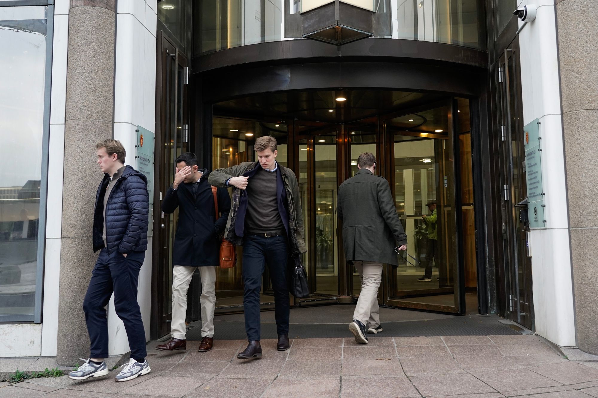 Aslak Digre, fra Palantir, forlater departementet etter et møte med digitaliseringsminister Karianne Tung. Han er i ferd med å ta på seg jakken, mens to andre representanter fra Palantir går ut sammen med ham.