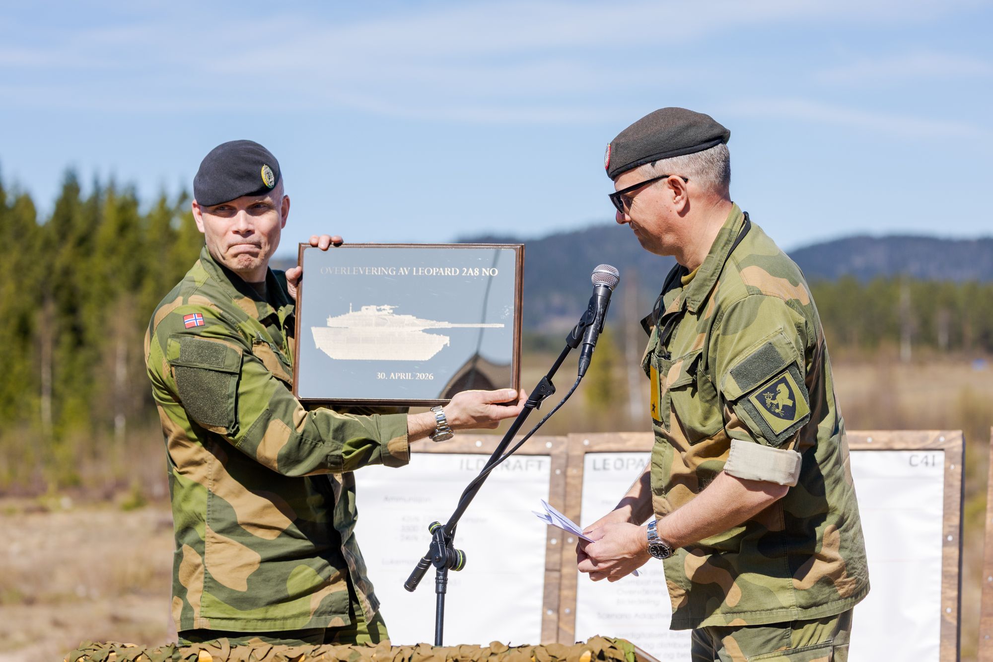 Brigader Trond Haande, sjef for Hærens våpenskole (t.v), mottar et bilde fra Tomas Beck, sjef for land- og felleskapasiteter i Forsvarsmateriell, som et symbol på mottakelsen av de første Leopard 2A8-stridsvognene.