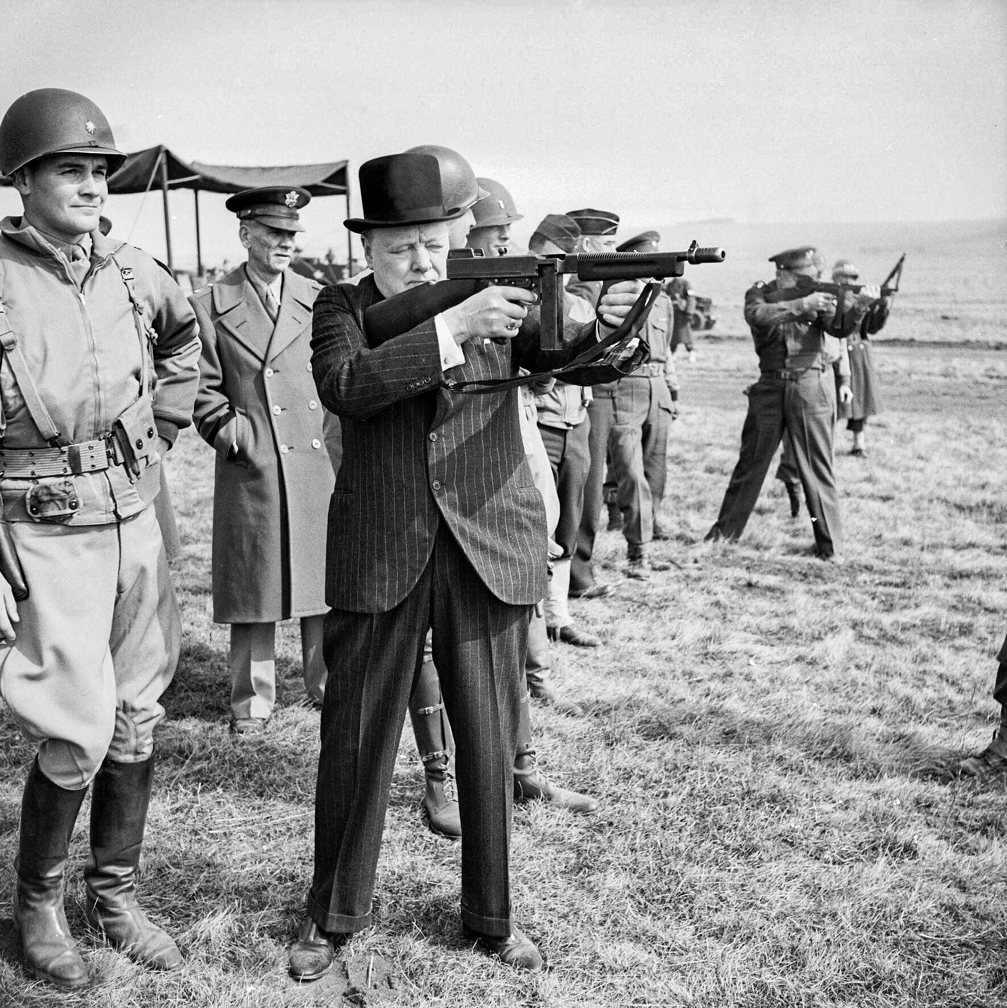 Statsminister Winston Churchill prøveskyter en Thompson M1 i mars 1944, og ser kanskje ikke så våpenvant ut her. Men han hadde langt mer personlig stridserfaring enn nesten alle andre statsoverhoder på denne tiden, og definitivt mye mer enn general Eisenhower (i bakgrunnen).